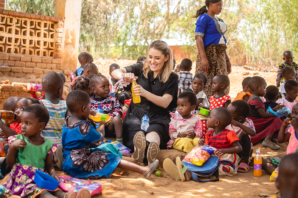 Ida Fladen sitter med ute med barnehagebarn i Malawi