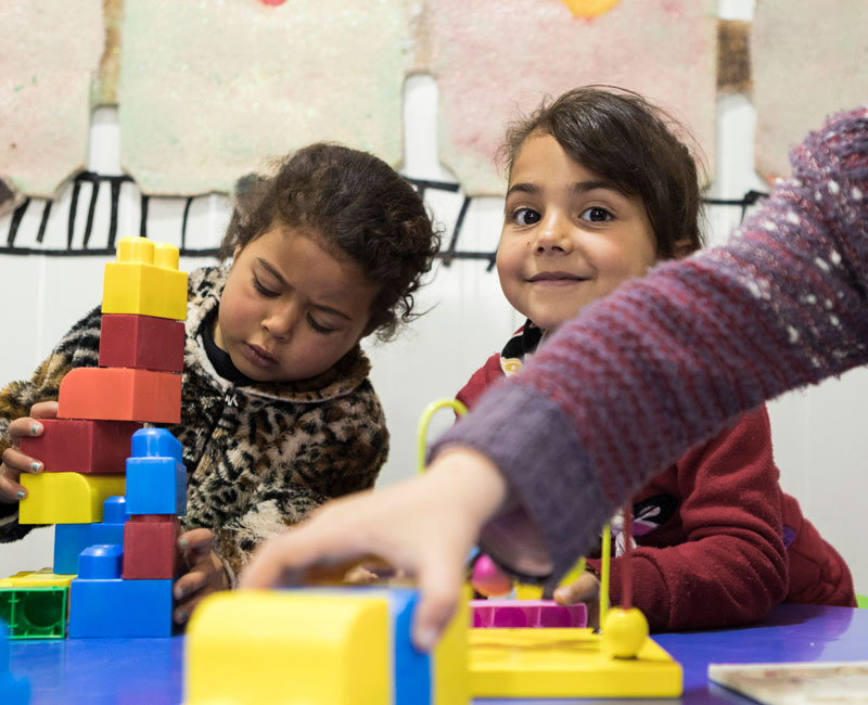 To syriske jenter leker med byggeklosser på støttesenter for flyktninger i Jordan