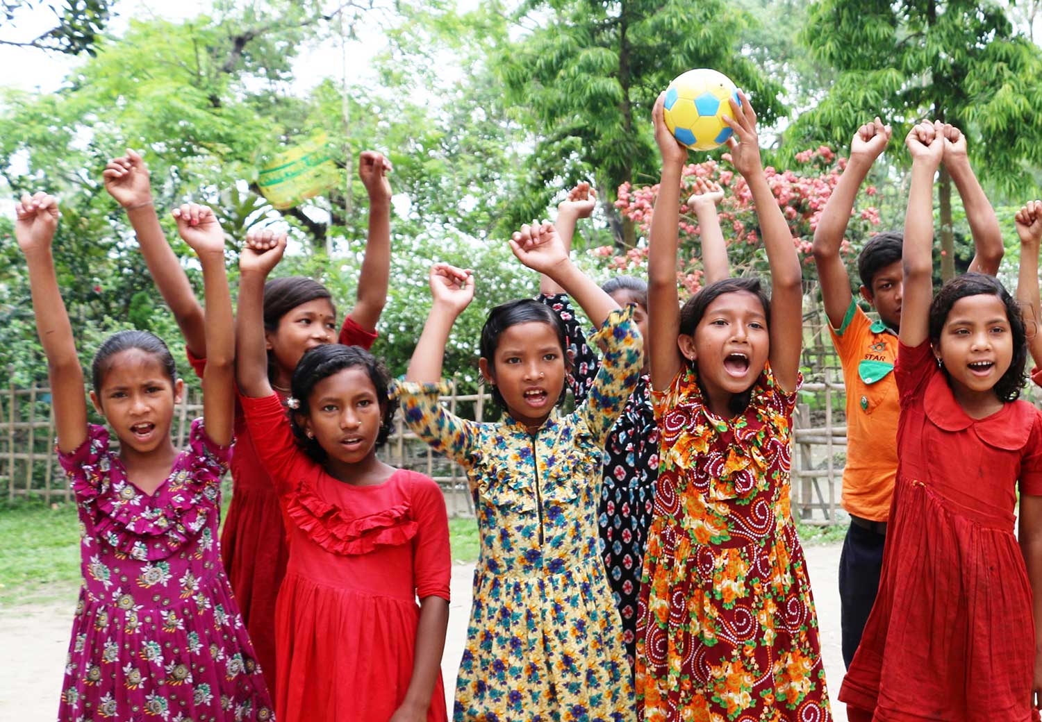 Jenter fra Bangladesh står med hendene i været.