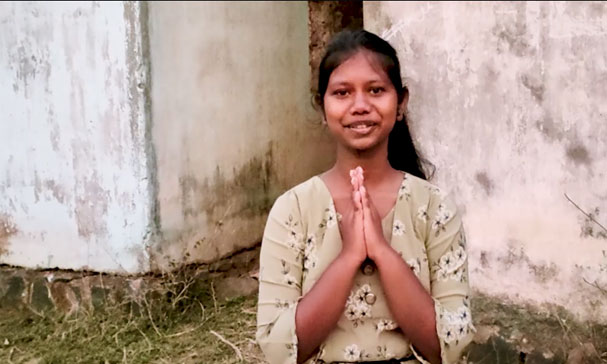 jente fra India står med håndflatene mot hverandre og ser inn i kamera
