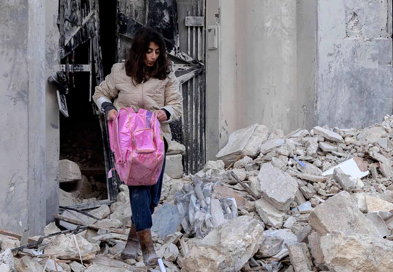 Kvinne bærer ut eiendeler fra ruinene etter jordskjelvet i Syria og Tyrkia.