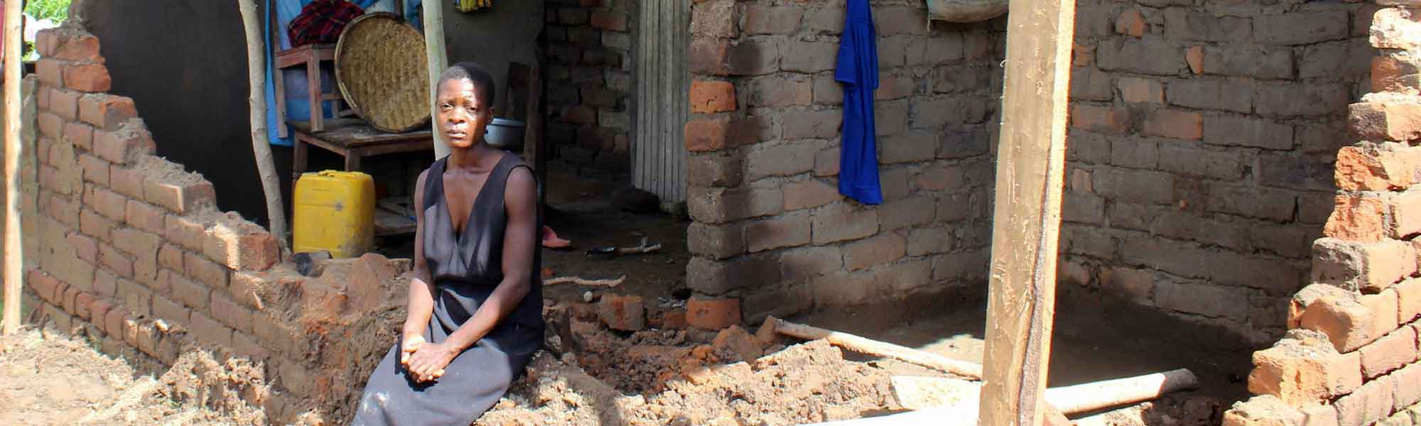 Bildet viser trebarnsmor Bertha fra Malawi utenfor familiens ødelagte hus