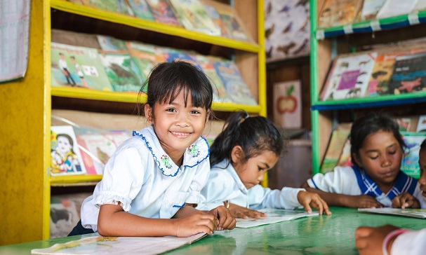 Jente smiler mot kamera i klasserom i Kambodsja