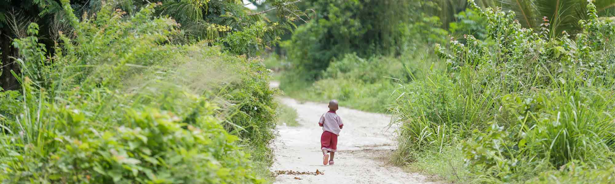 Et barn går bortover landeveien i Tanzania