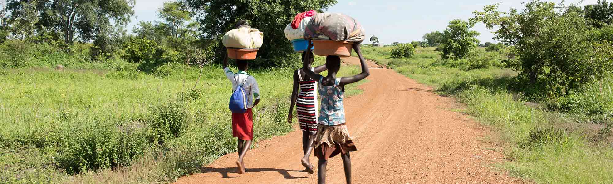 Tre jenter på vei til elva for å vaske klær i Sør Sudan