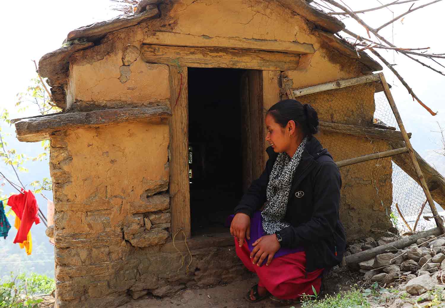Ambika fra Nepal sitter utenfor en mensenhytte.