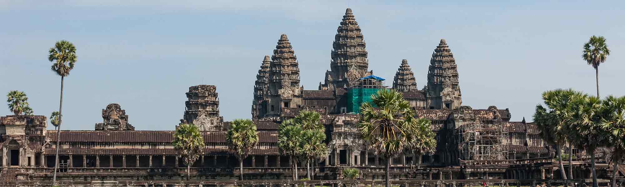 Gammelt tempel med noen palmer i kambodjsa