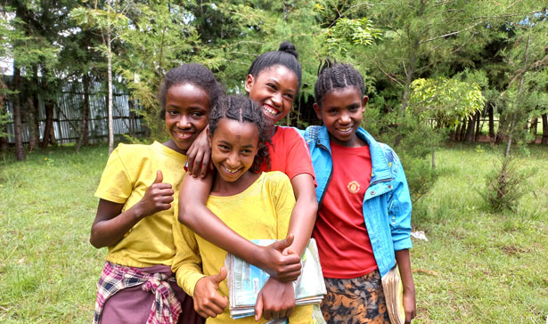 Venninner smiler mot kameraet utendørs i grønn hage i Etiopia
