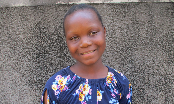 Jente smiler mot kamera utendørs i Mosambik