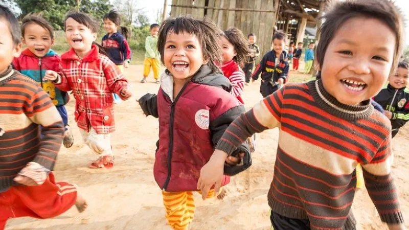 Vietnamesiske barn i førskolealder, løper og smiler