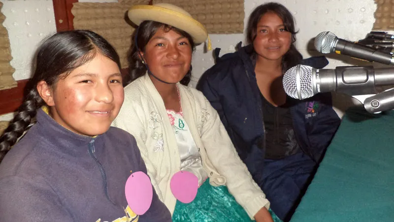 Tre jenter fra Bolivia foran radiomikrofoner