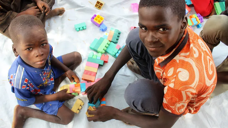 17-åring bygger klosser sammen med en liten gutt. Niger