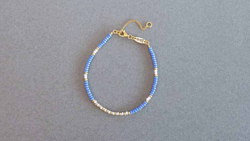 Gave med mening: Perlearmbånd med glassperler i blå, gull og hvit. Sølvlås. Foto.