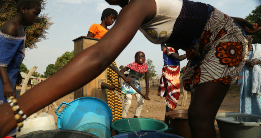 En gruppe mennesker henter vann fra vannpumpe