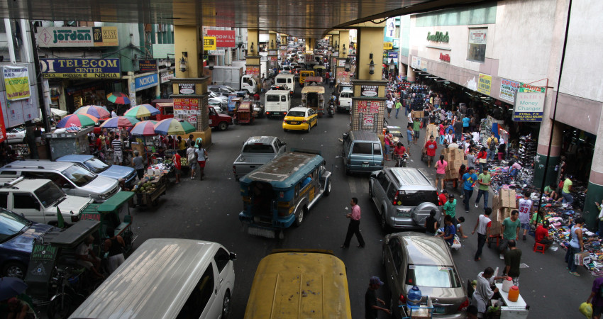 Biler, busser og mennesker om hverander i veibildet i Manila