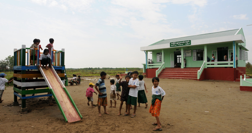 barn leker på en sklie utefor en liten skole