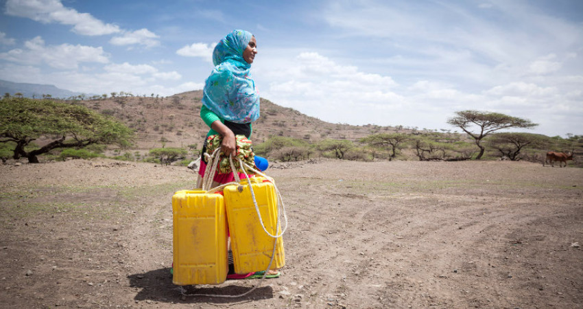 Woman fetching water with two yellow buckets