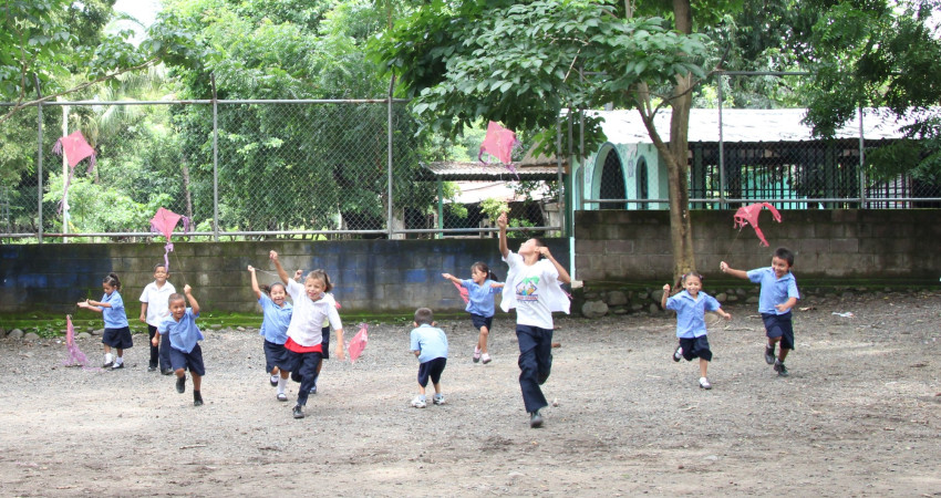 En flokk med barn løper mot kamera med drager