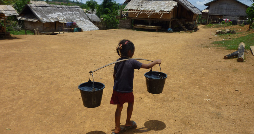 En liten jente barer to fulle bøtter med vann over skuldrene