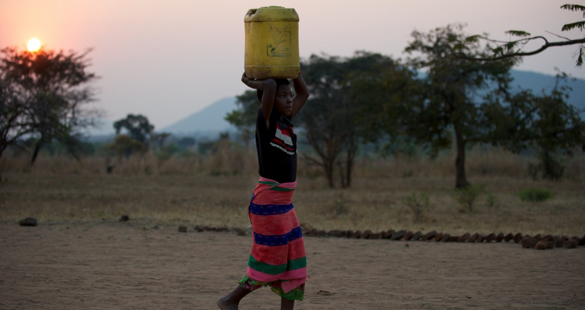 En jente bærer en kanne med vann på hodet