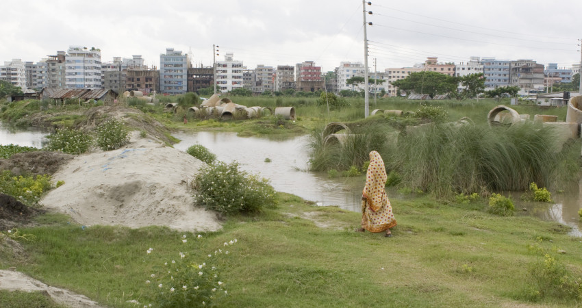 en jente går over en gresslette utenfor Dhaka