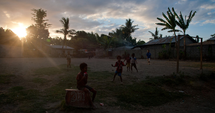 Barn leker på landsbyens fotballbane i solnedgang