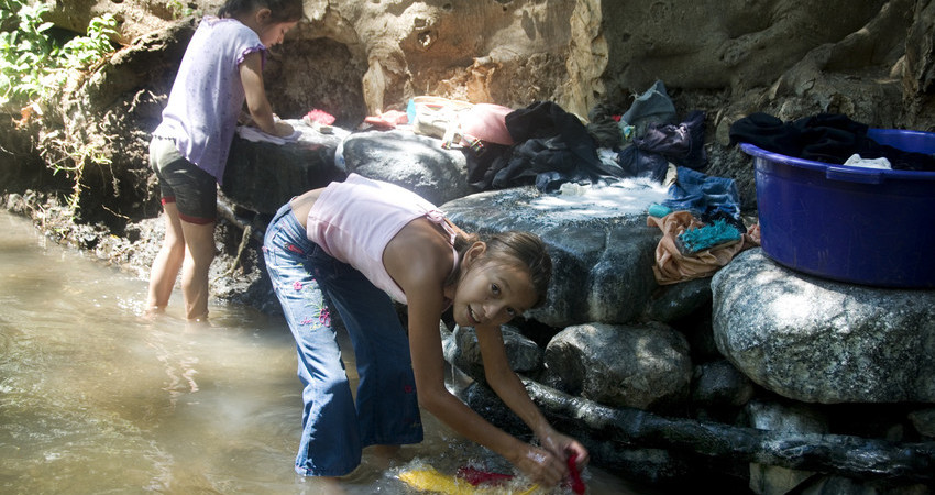 To jenter vasker klær i elven