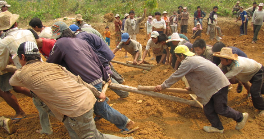 En gruppe landsbybeboere pløyer jorden klar for å bygge en skole