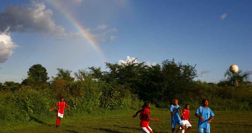 fem jenter spiller fotball på en gresslette