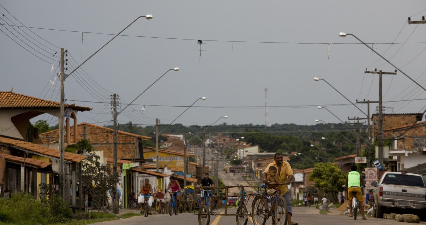 En mann triller sykkelen sin over veien i byen São Luis