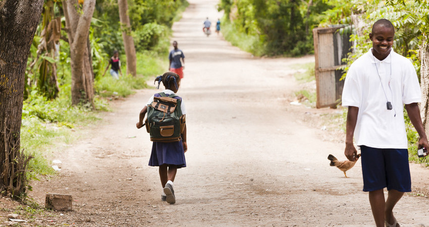 En jente går bortover en vei med skolesekk