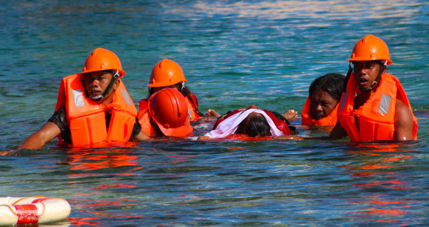 Seks personer i orange uniformer øver på å redde en person ut fra havet som en del av beredskapsøvelse