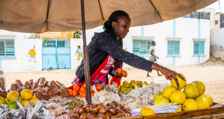 Ung kvinne selger frukt langs veien