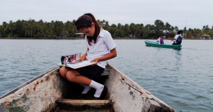 En jente tar båten over elven til skolen
