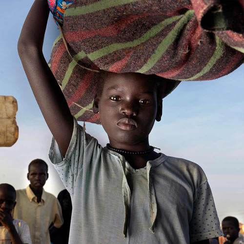 Gutt fra Sudan bærer mat på hodet.