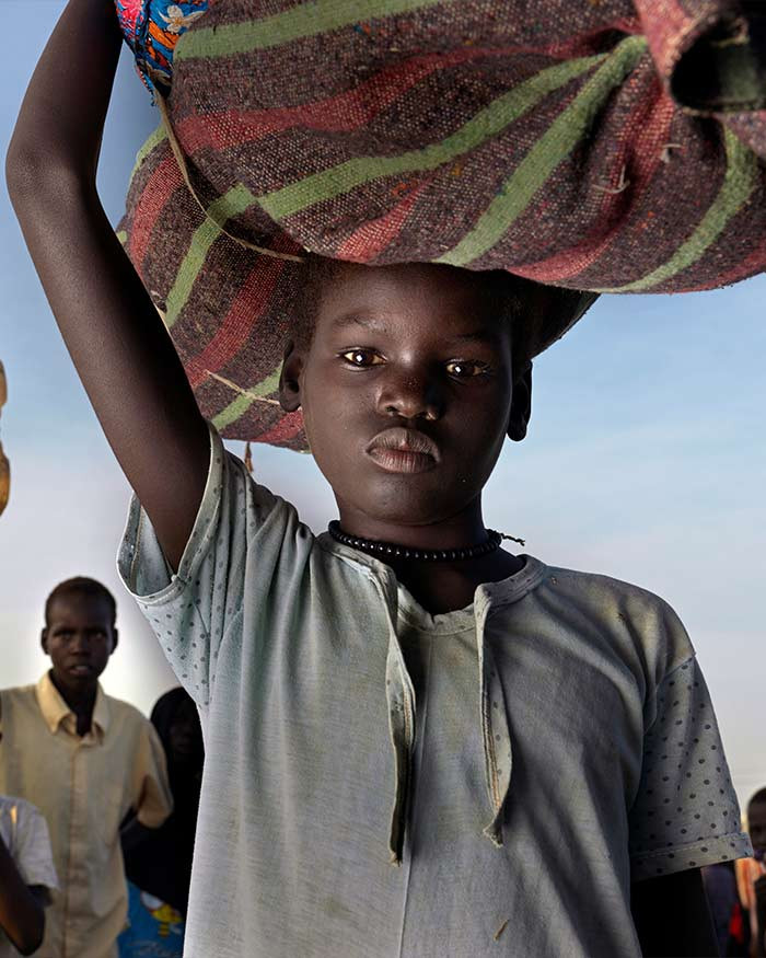 Gutt fra Sudan bærer mat på hodet.