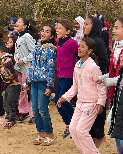Barn synger og leker i en trygg sone i Gaza