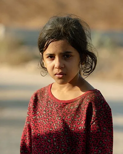 Ei jente står å ser rett i kameraet.