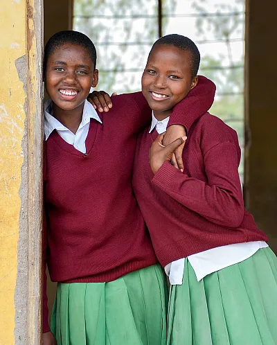 Jenter som holder rundt hverandre og smiler.