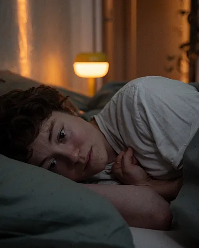 Jente som ligger i senga og ser redd ut.