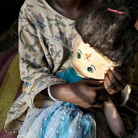 Jente fra Sør-Sudan holder rundt dukken sin.