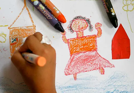 Et fadderbarn sitter å tegner en tegning til fadderen sin.