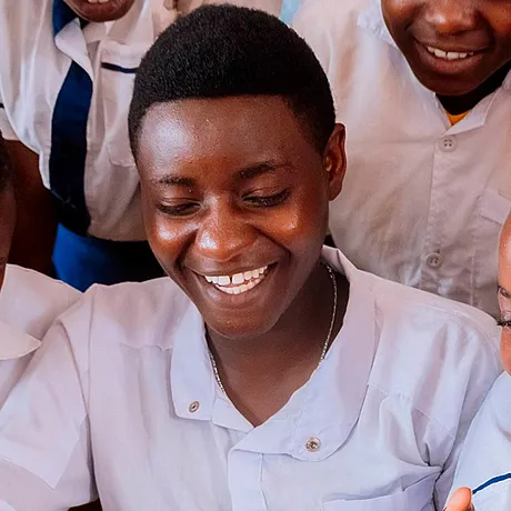 Skolejenter fra Rwanda som ler og ser på en bok