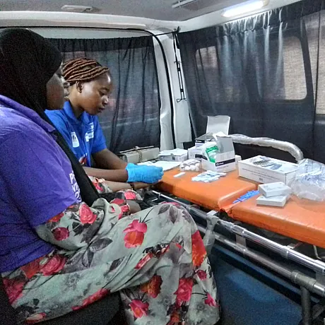 Helsearbeider fra Plan gjør helsesjekk for kjønnssykdommer på kvinne i Guinea i en mobil helsevan