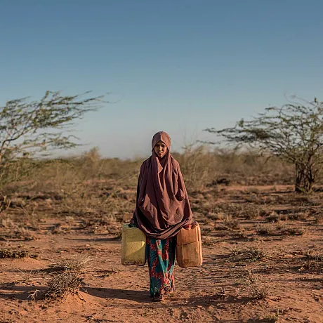 Jente som bærer to vannkanner i Somalia