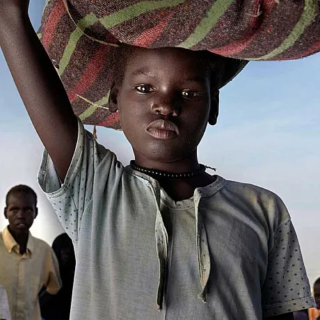 Gutt fra Sudan bærer mat på hodet.