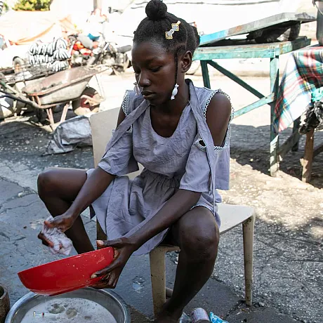 Isabelle fra Haiti vasker opp utenfor hjemmet sitt.