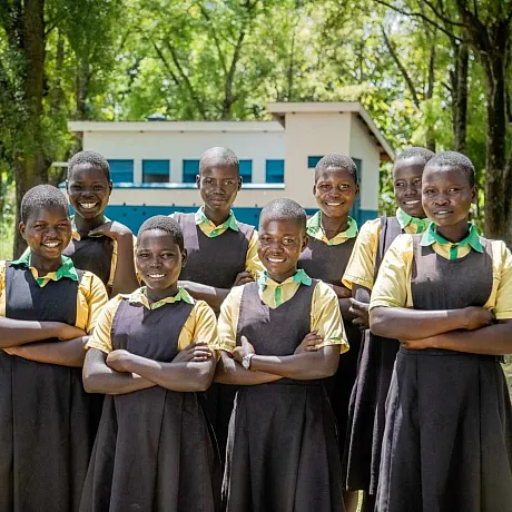 Jenter stående med armene i kryss på skolen i Uganda