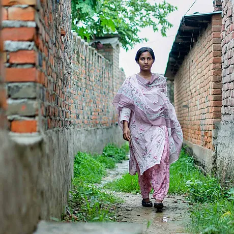 Jente, aktivist går mellom hus i Nepal