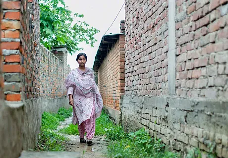 Jente, aktivist går mellom hus i Nepal